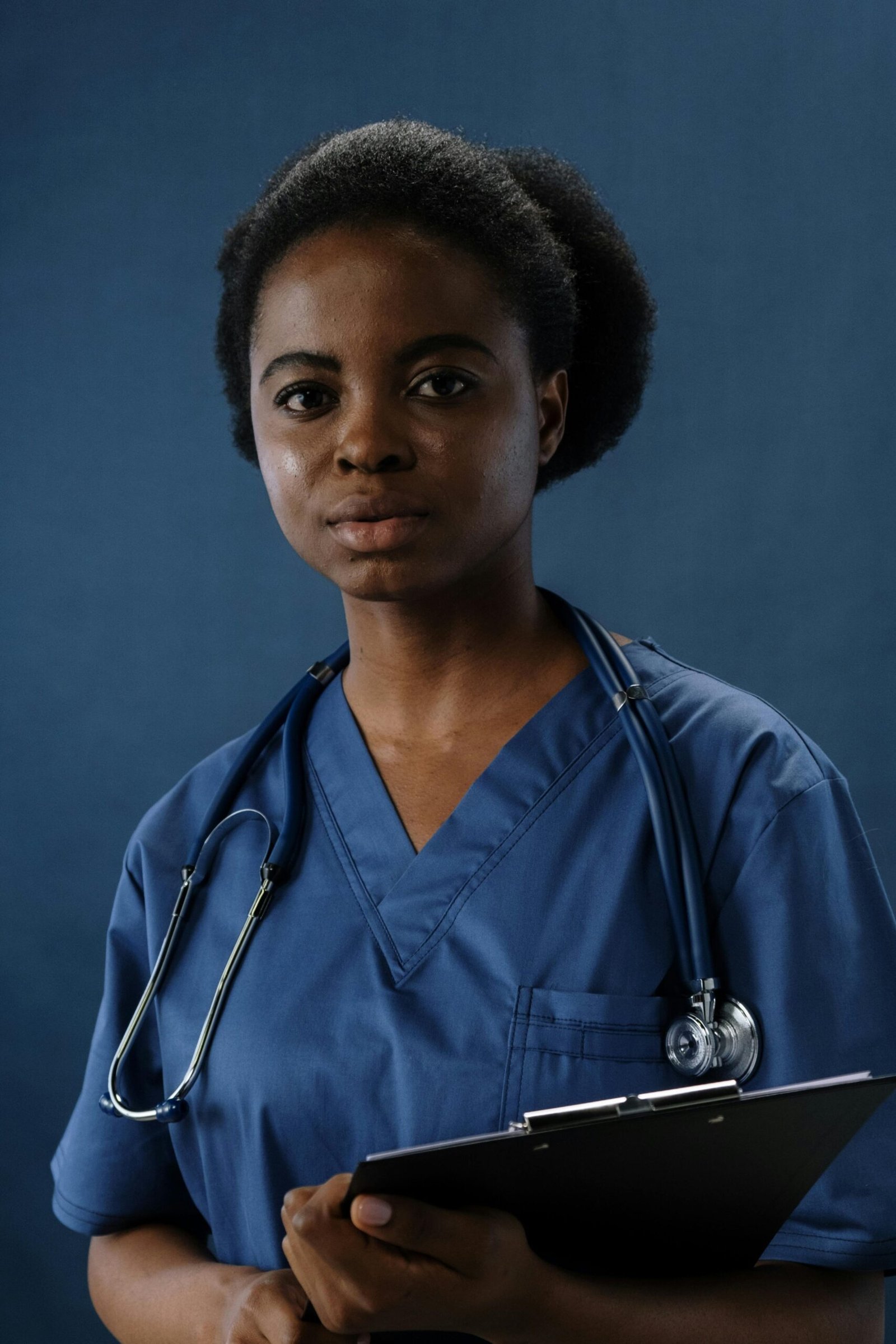 Professional nurse in blue scrubs holding a clipboard, conveying confidence and care.
